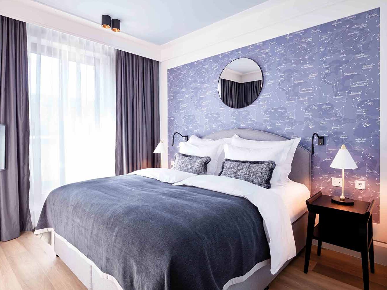 hotel hamburg innenstadt. Ein Hotelbett im TORTUE Hamburg in einem Raum mit blauer Tapete, hölzernem Boden und großen Fenstern.